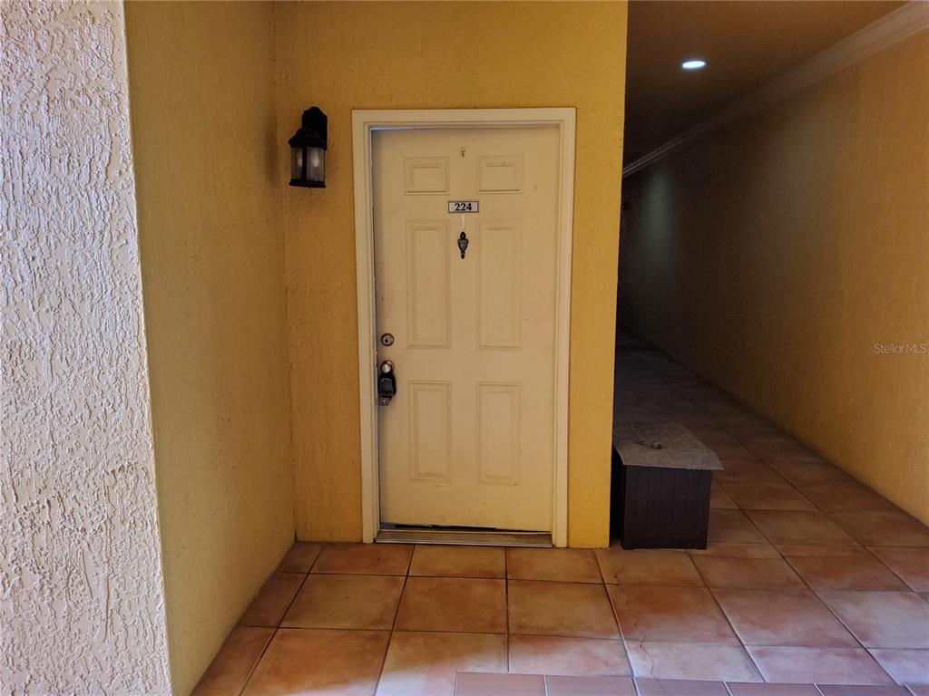 A white front door with a lockbox is set in a yellow exterior wall — 4333 BAYSIDE VILLAGE DRIVE UNIT 224, TAMPA, FL