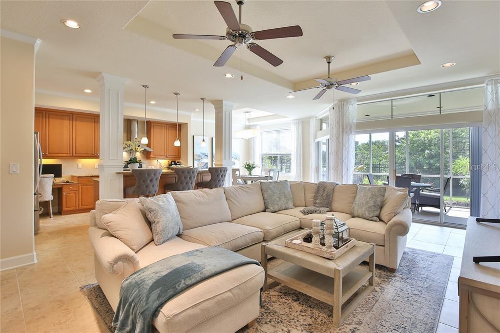 A spacious open-concept living room features a large sectional sofa, kitchen island, and sliding doors — 7919 ST SIMONS STREET, UNIVERSITY PARK, FL