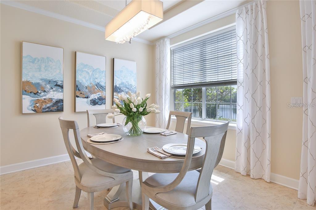 A dining room features an oval table, four chairs, abstract wall art, and a window view — 7919 ST SIMONS STREET, UNIVERSITY PARK, FL