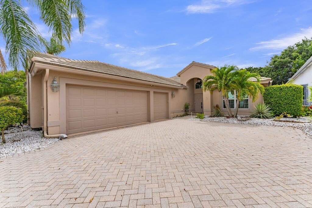 A tan house with a three-car garage and a paved driveway under a blue sky — 6429 Three Lakes, Boynton Beach FL 33437, BOYNTON BEACH, FL