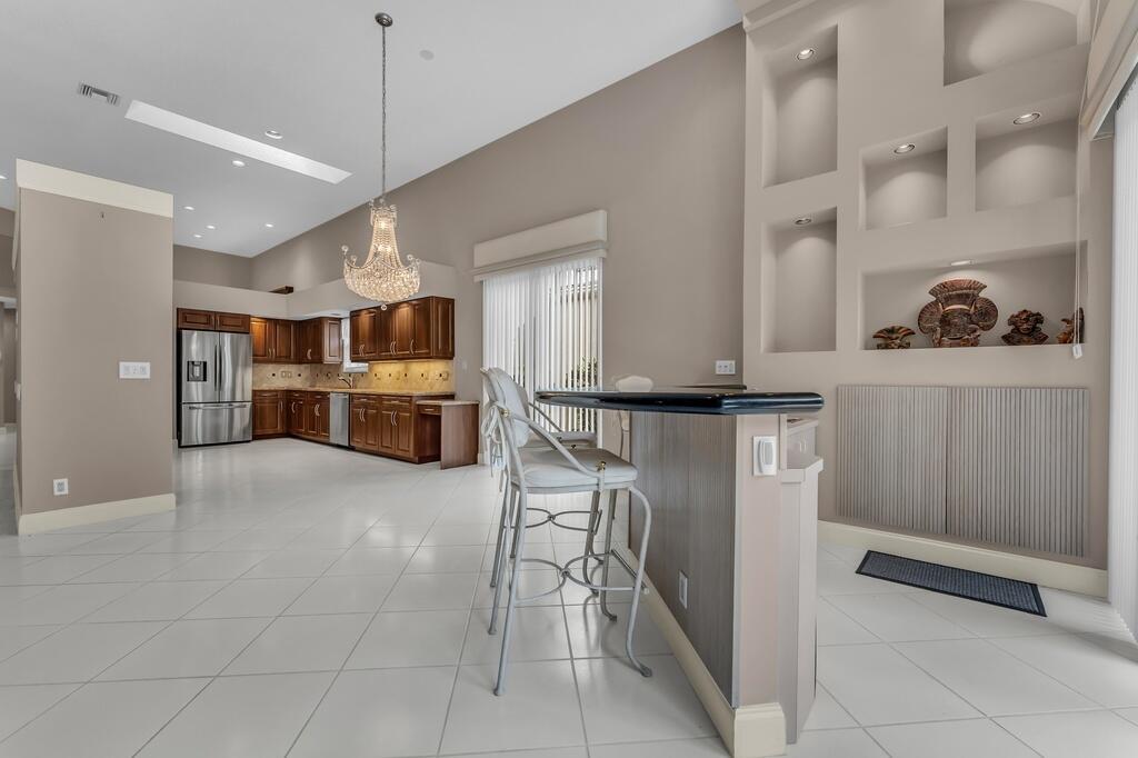 A kitchen with wood cabinets, a breakfast bar, and a chandelier over a tiled floor — 6429 Three Lakes, Boynton Beach FL 33437, BOYNTON BEACH, FL