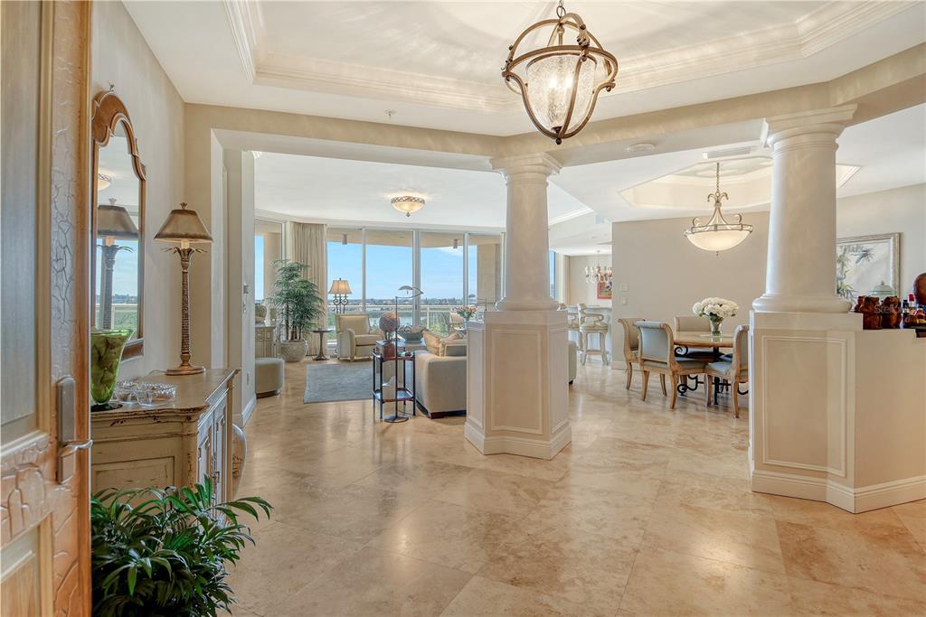 An open-concept foyer with stone flooring leads to a living area and dining room — 1300 BENJAMIN FRANKLIN DRIVE UNIT 709, SARASOTA, FL