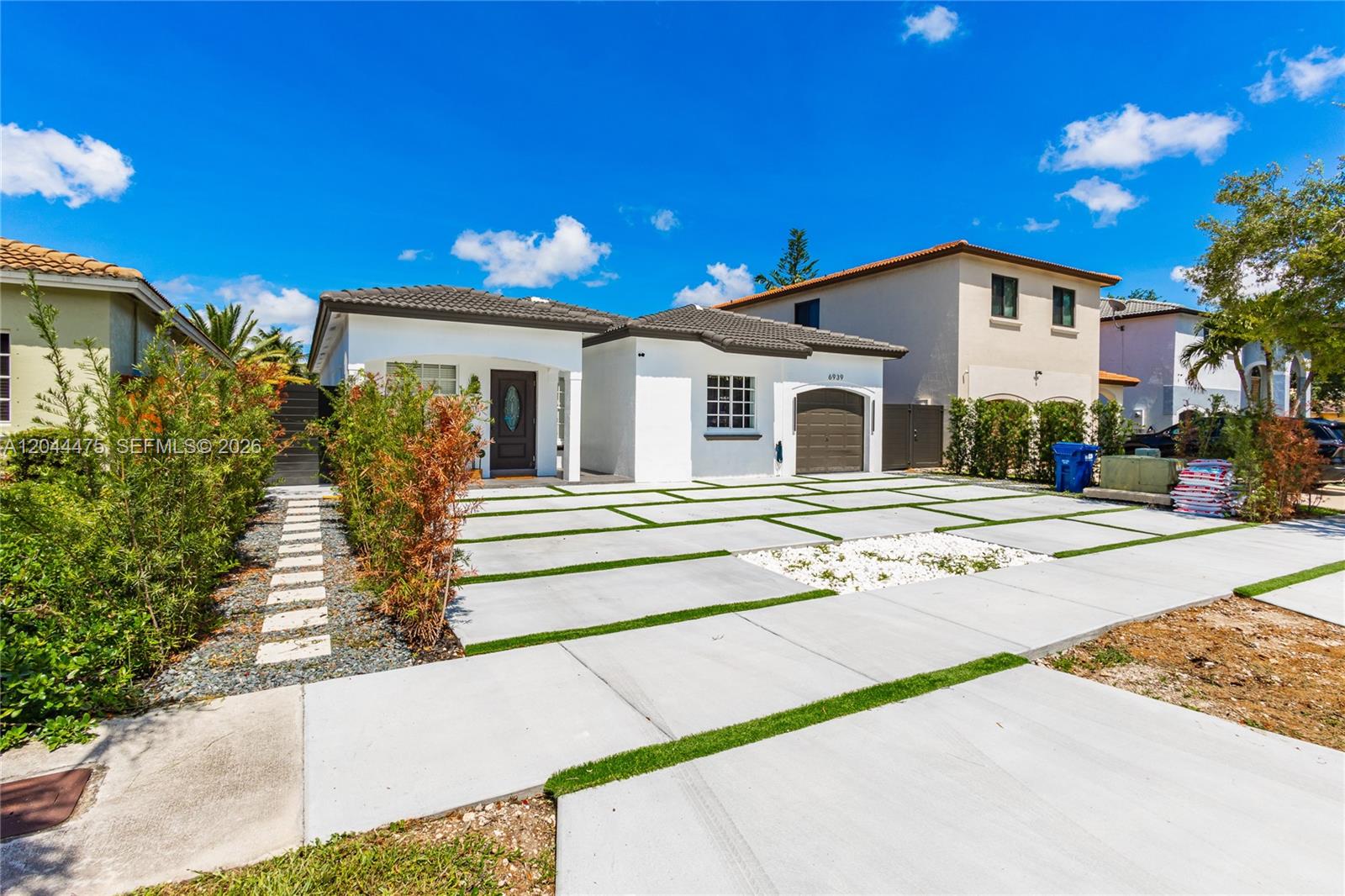 A single-story white house features a modern concrete paver driveway with integrated grass strips — 6939 SW 158th Ave, Miami FL 33193, MIAMI, FL