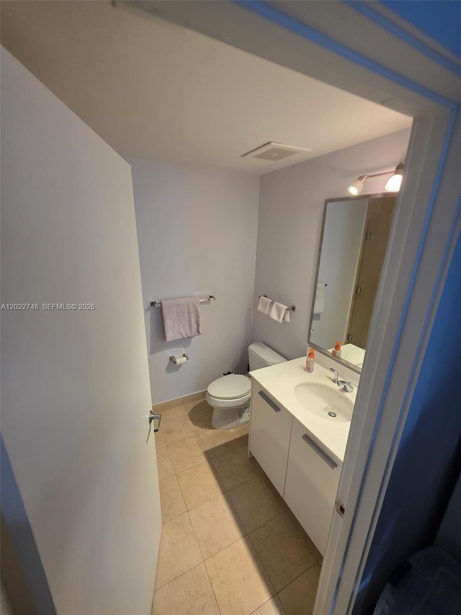 A small bathroom features a white vanity, a toilet, and light-colored tile flooring — 1060 Brickell Ave # 2201, Miami FL 33131, MIAMI, FL