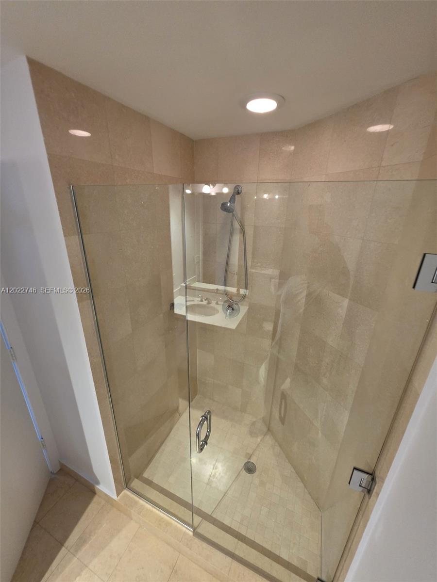 A glass-enclosed shower with beige tile walls and a handheld showerhead — 1060 Brickell Ave # 2201, Miami FL 33131, MIAMI, FL