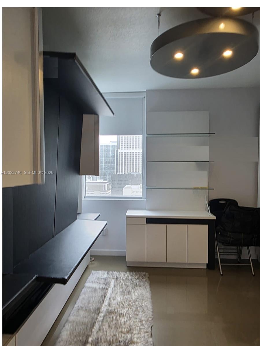 A modern room features a black wall unit, white cabinetry with glass shelves, and city views — 1060 Brickell Ave # 2201, Miami FL 33131, MIAMI, FL