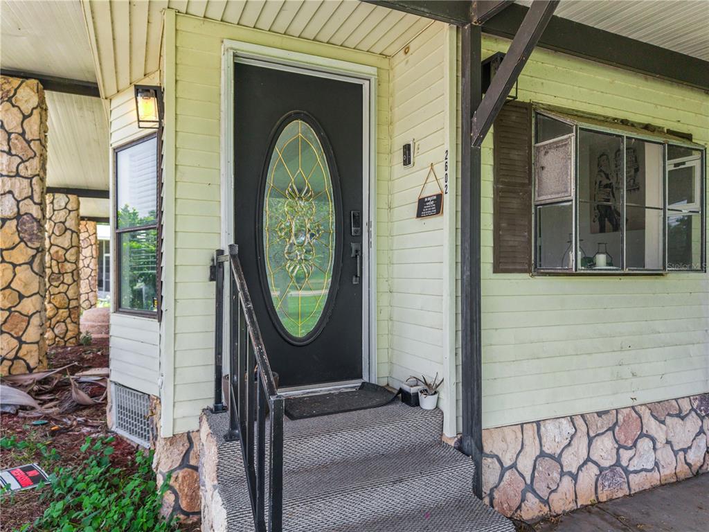 The exterior of a house features a black front door with an oval glass insert — 2602 EINWOOD DRIVE, KISSIMMEE, FL