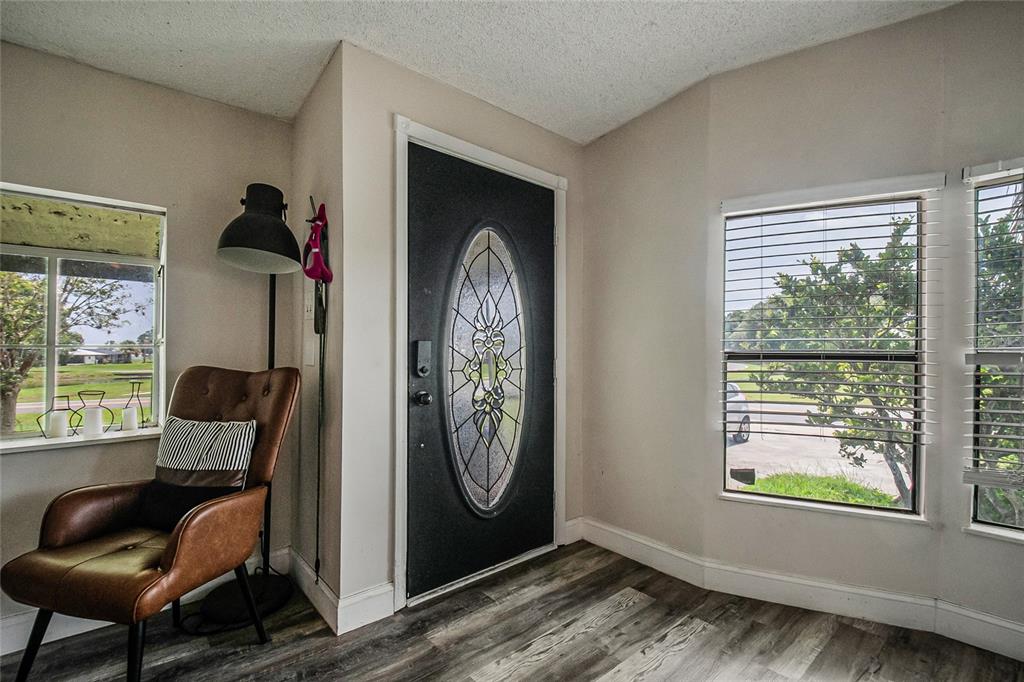 An entryway features a dark front door with a decorative oval glass insert and wood-look flooring — 2602 EINWOOD DRIVE, KISSIMMEE, FL