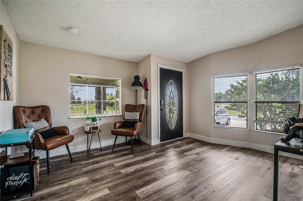 A living room with wood-look flooring, two leather chairs, and a front door with glass — 2602 EINWOOD DRIVE, KISSIMMEE, FL
