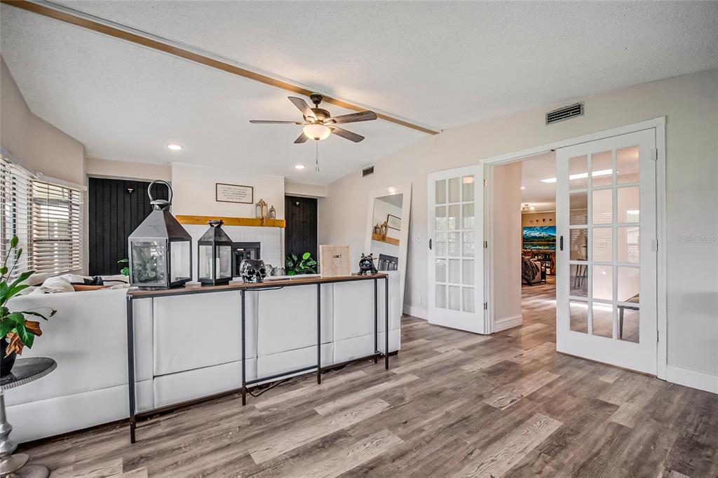 A living room features a white sofa, a console table, a fireplace, and French doors — 2602 EINWOOD DRIVE, KISSIMMEE, FL