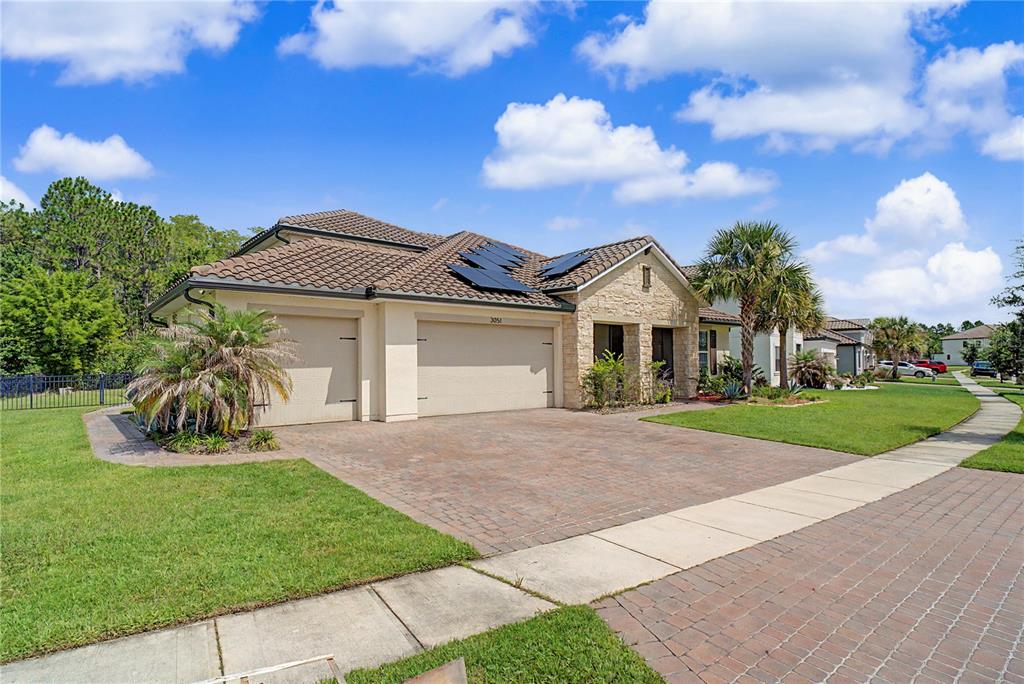 A single-story house with a tiled roof, solar panels, and a brick driveway — 3051 AGOSTINO TERRACE, KISSIMMEE, FL