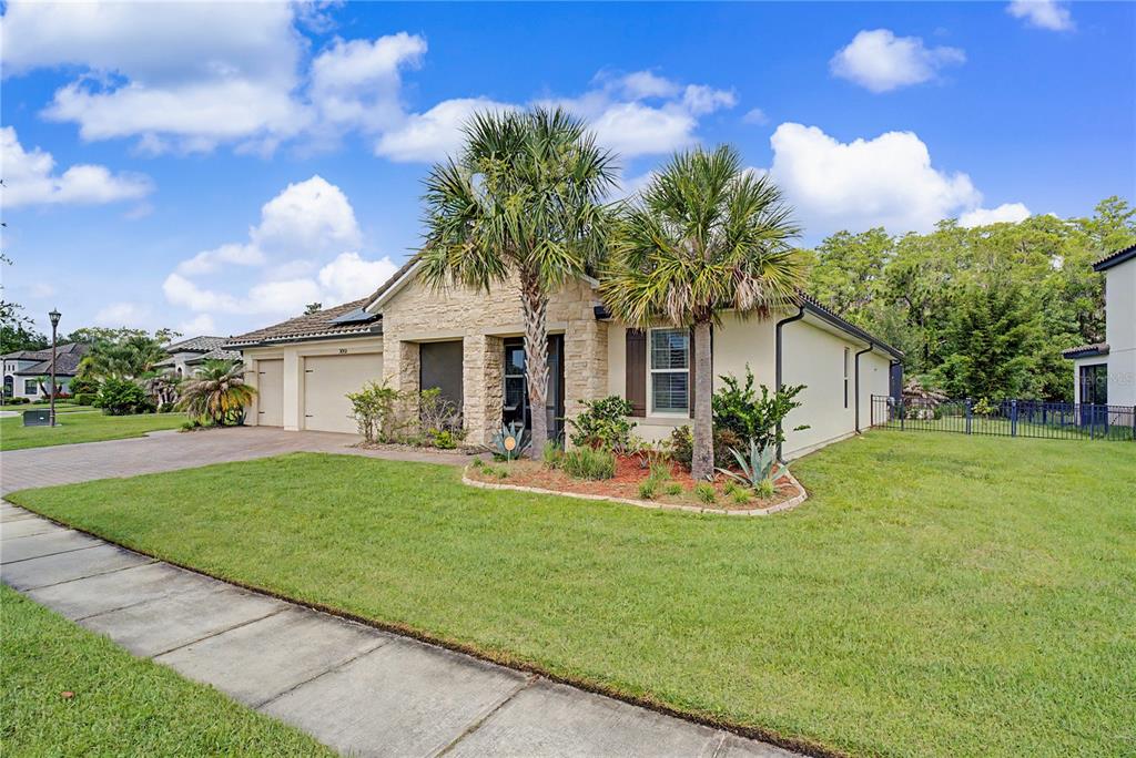 A single-story house with a stone facade, two-car garage, and two palm trees in front — 3051 AGOSTINO TERRACE, KISSIMMEE, FL