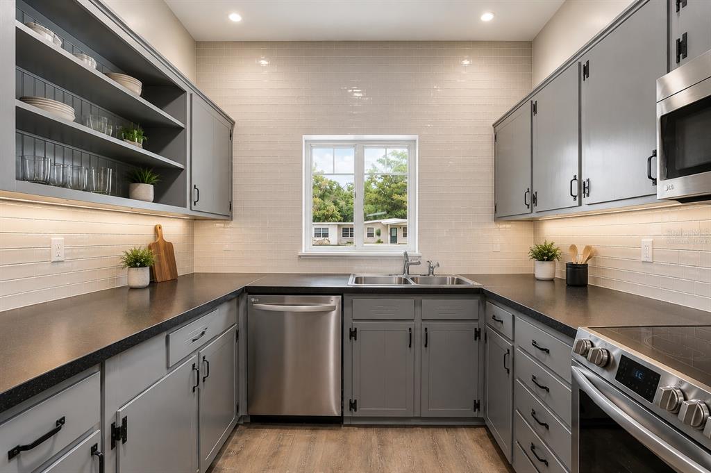 A kitchen with grey cabinets, dark countertops, stainless steel appliances, and a window above the sink — 8616 SHIRLEY DRIVE, TEMPLE TERRACE, FL