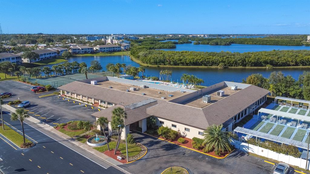 An aerial view shows a low-rise building with a parking lot and adjacent tennis courts — 9860 62ND TERRACE N UNIT 1014, ST PETERSBURG, FL