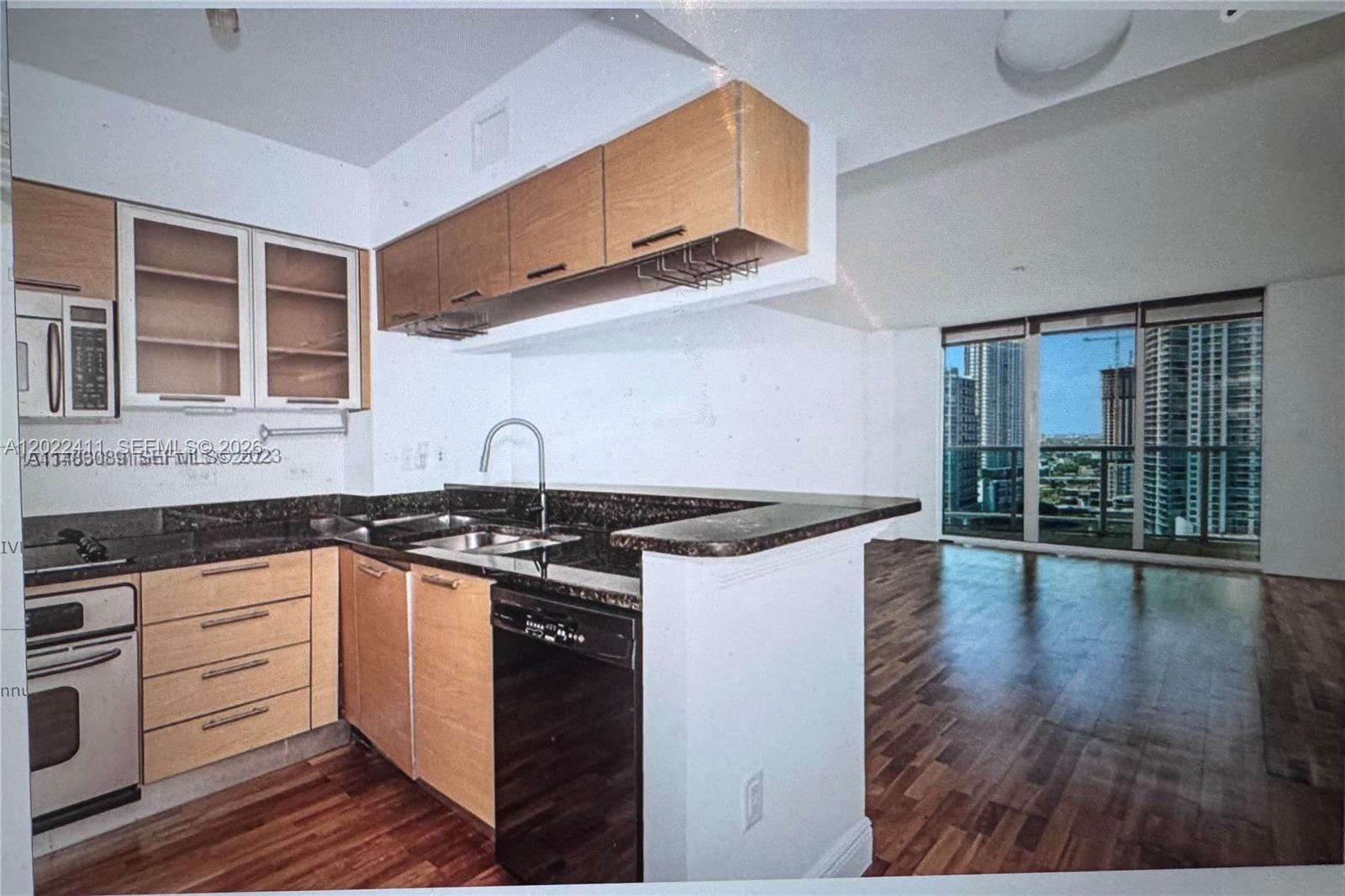 A kitchen with light wood cabinets, dark countertops, and a view of city high-rises — 31 SE 5th St # 2507, Miami FL 33131, MIAMI, FL