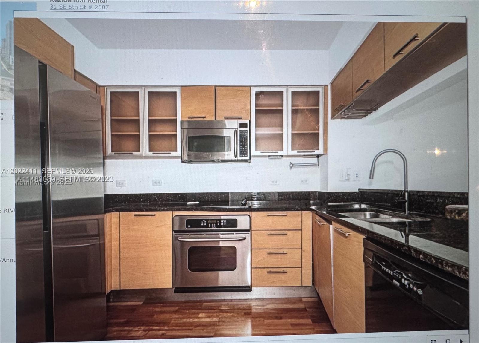 A kitchen features light wood cabinets, stainless steel appliances, and dark granite countertops — 31 SE 5th St # 2507, Miami FL 33131, MIAMI, FL