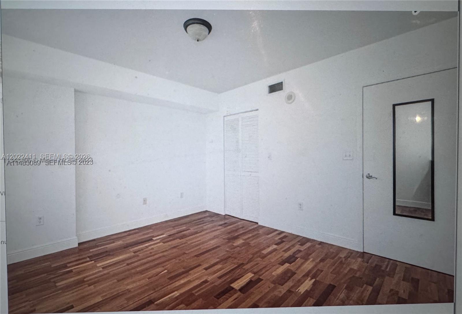 An empty room features white walls, wood flooring, a ceiling light, and a closet — 31 SE 5th St # 2507, Miami FL 33131, MIAMI, FL