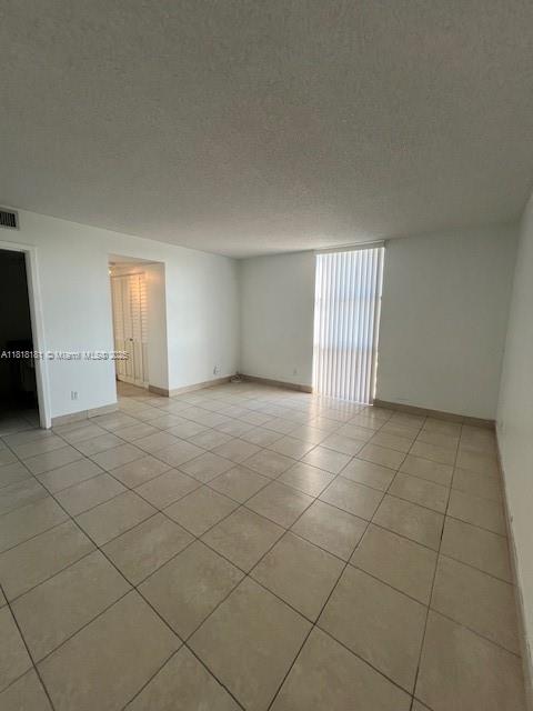 An empty room with beige tile flooring, white walls, and a large window with vertical blinds — 13499 Biscayne Blvd # 602, North Miami FL 33181, NORTH MIAMI, FL
