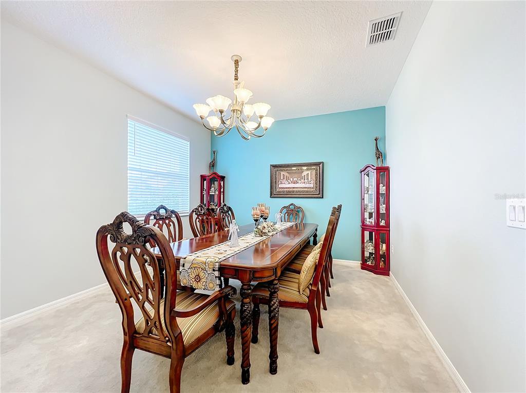 A formal dining room features a wooden table, upholstered chairs, and a blue accent wall — 172 SEVILLE DRIVE, DAVENPORT, FL