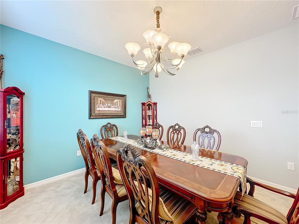 A dining room features a wooden table, ornate chairs, a chandelier, and a blue accent wall — 172 SEVILLE DRIVE, DAVENPORT, FL