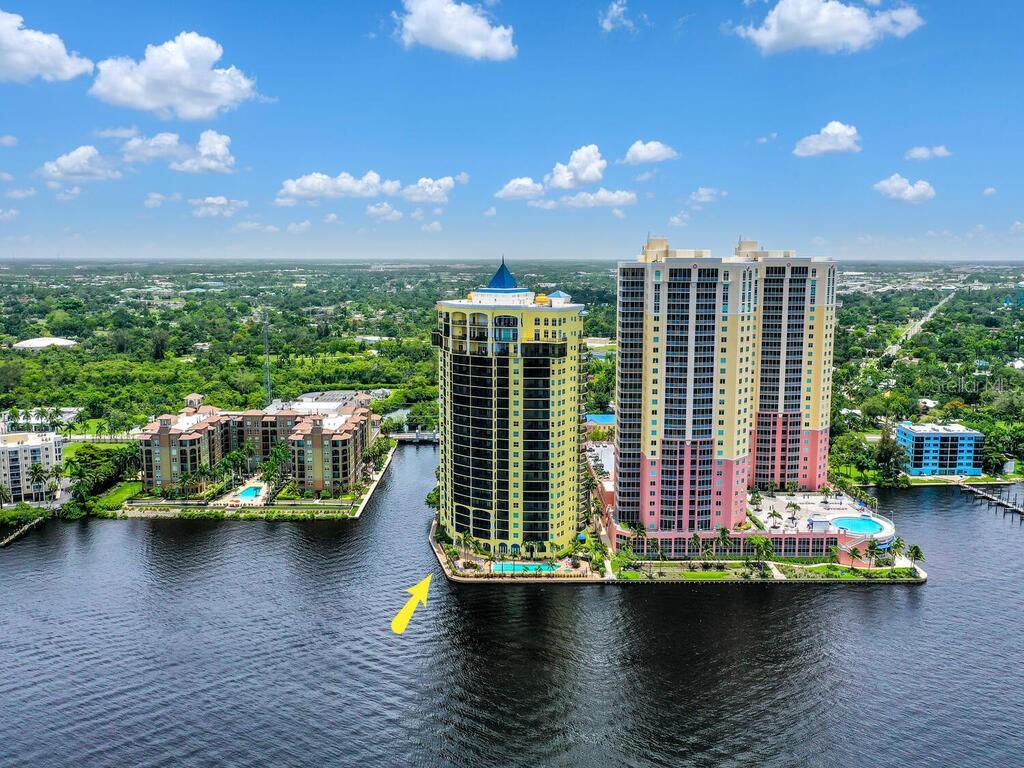 An aerial view of a tall yellow residential tower situated on a waterfront property — 2797 1ST STREET UNIT 1605, FORT MYERS, FL
