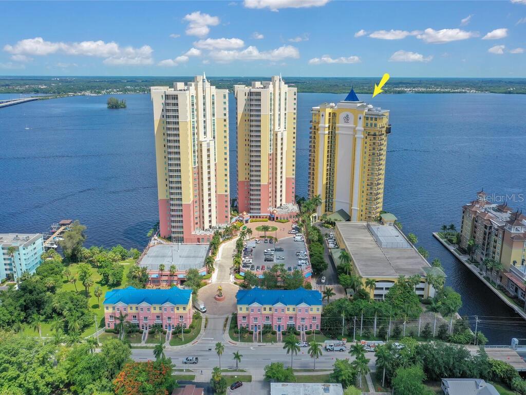 An aerial view shows three tall residential towers and smaller buildings situated along a waterfront — 2797 1ST STREET UNIT 1605, FORT MYERS, FL