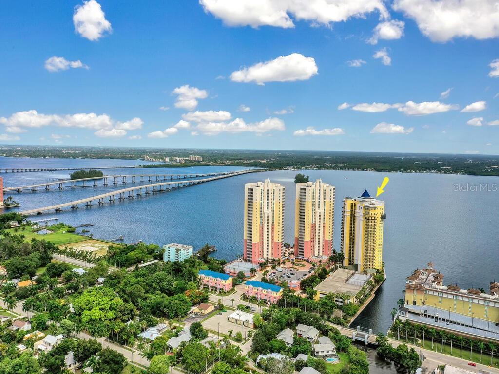 An aerial view shows high-rise residential buildings situated on a waterfront near a long bridge — 2797 1ST STREET UNIT 1605, FORT MYERS, FL
