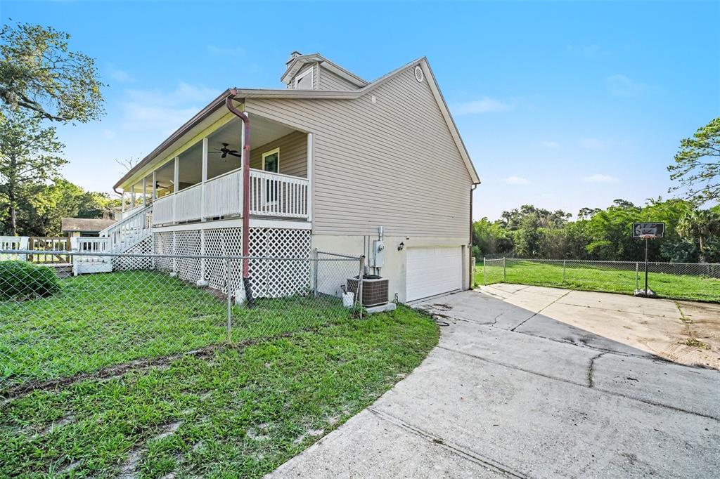 The exterior of a two-story house features beige siding, a screened porch, and a concrete driveway — 5710 BARNA AVENUE, TITUSVILLE, FL