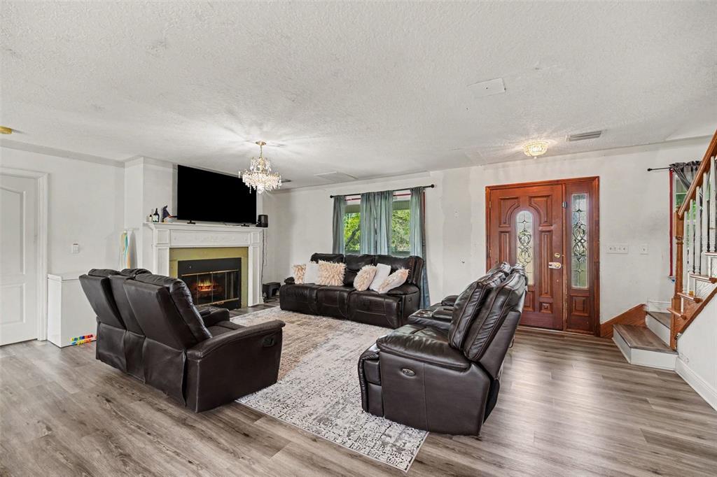 A living room features dark leather furniture, a fireplace, and wood-look flooring — 5710 BARNA AVENUE, TITUSVILLE, FL