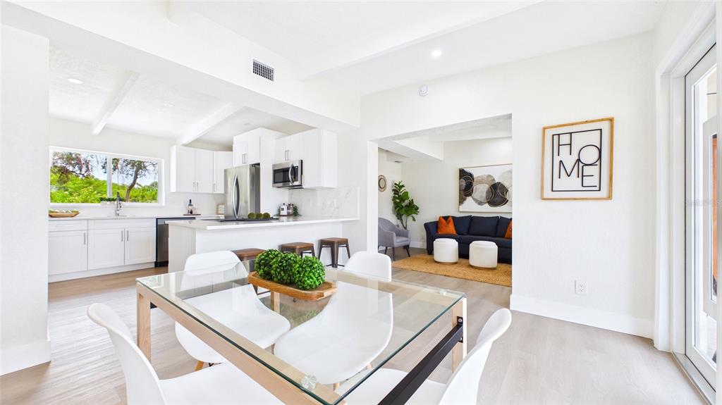 A bright, open-concept dining area, kitchen, and living room with white cabinetry and light flooring — 4103 W PEARL AVENUE, TAMPA, FL