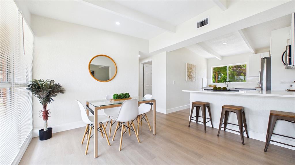 A dining area with a glass table and white chairs sits adjacent to a kitchen — 4103 W PEARL AVENUE, TAMPA, FL