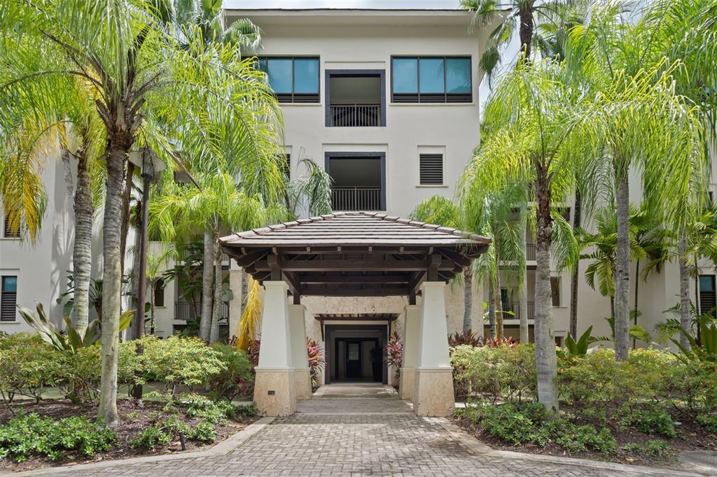 A paved walkway leads to the covered entrance of a multi-story building surrounded by palm trees — Bahia Beach Resort LAS VENTANAS II UNIT 104, RIO GRANDE, PR