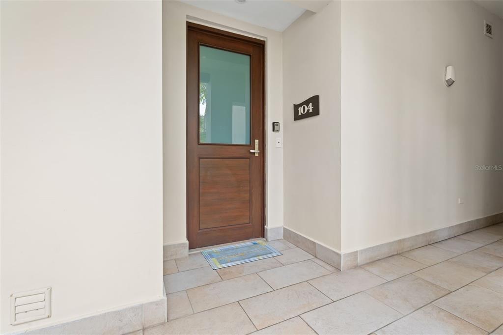 A wooden front door with a glass panel is set in a tiled entryway — Bahia Beach Resort LAS VENTANAS II UNIT 104, RIO GRANDE, PR