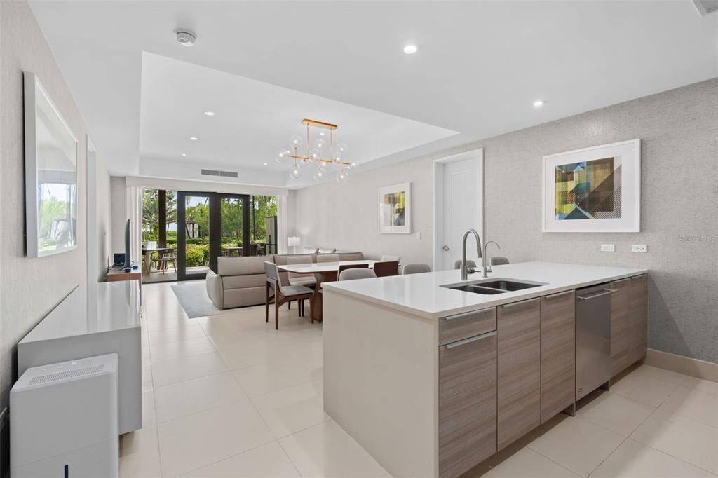 A modern kitchen with wood-toned cabinets and a white island opens to a dining area — Bahia Beach Resort LAS VENTANAS II UNIT 104, RIO GRANDE, PR