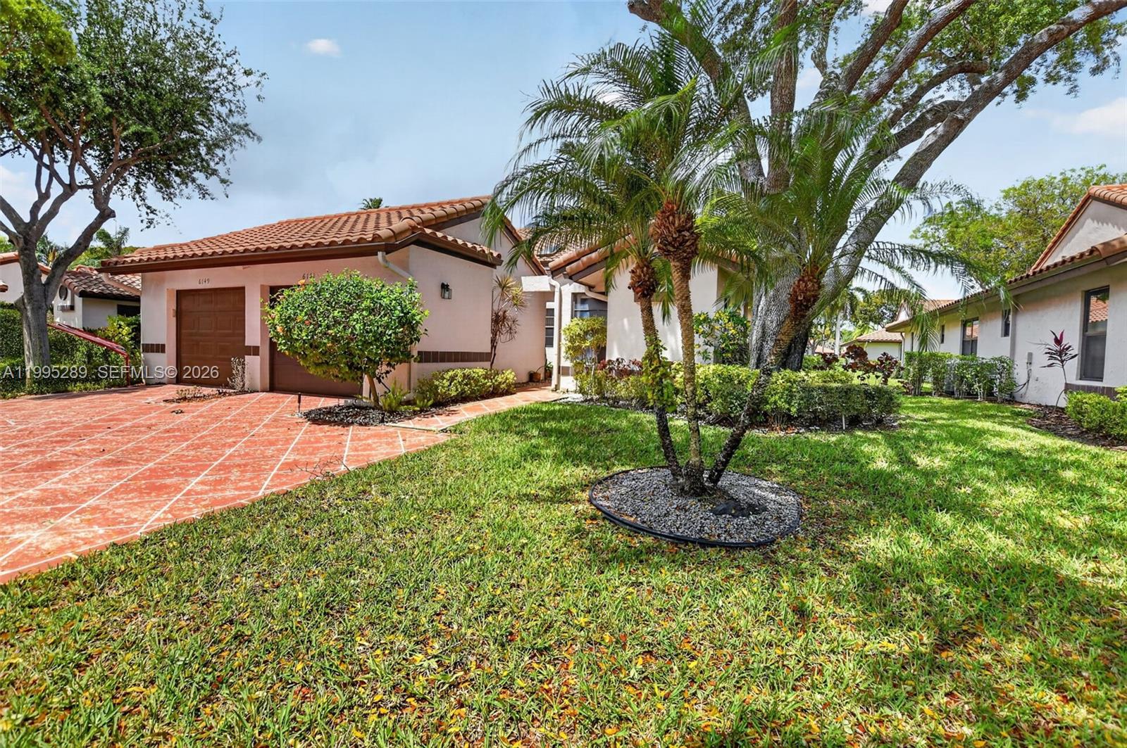A single-story house with a tiled roof, a patterned driveway, and a palm tree — 6141 SE Sunny Pointe Cir, Delray Beach FL 33484, DELRAY BEACH, FL