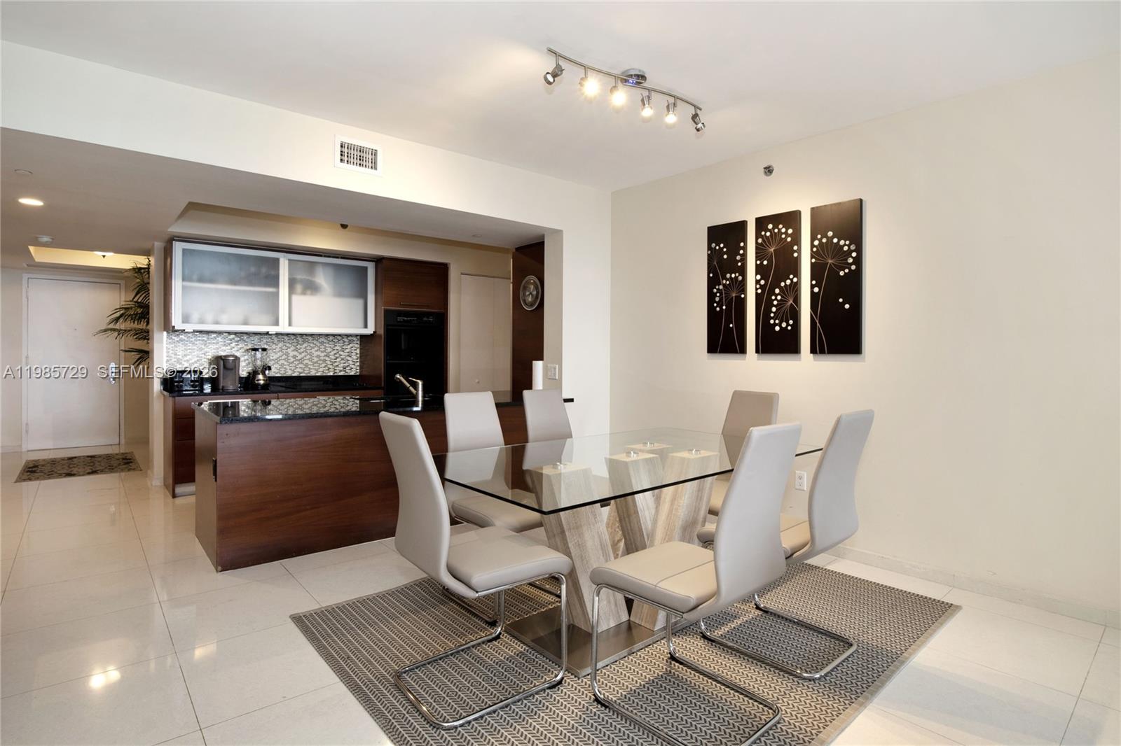 A dining area with a glass table and six chairs sits adjacent to a kitchen — 1830 S OCEAN DR # 3204, Hallandale Beach FL 33009, HALLANDALE BEACH, FL