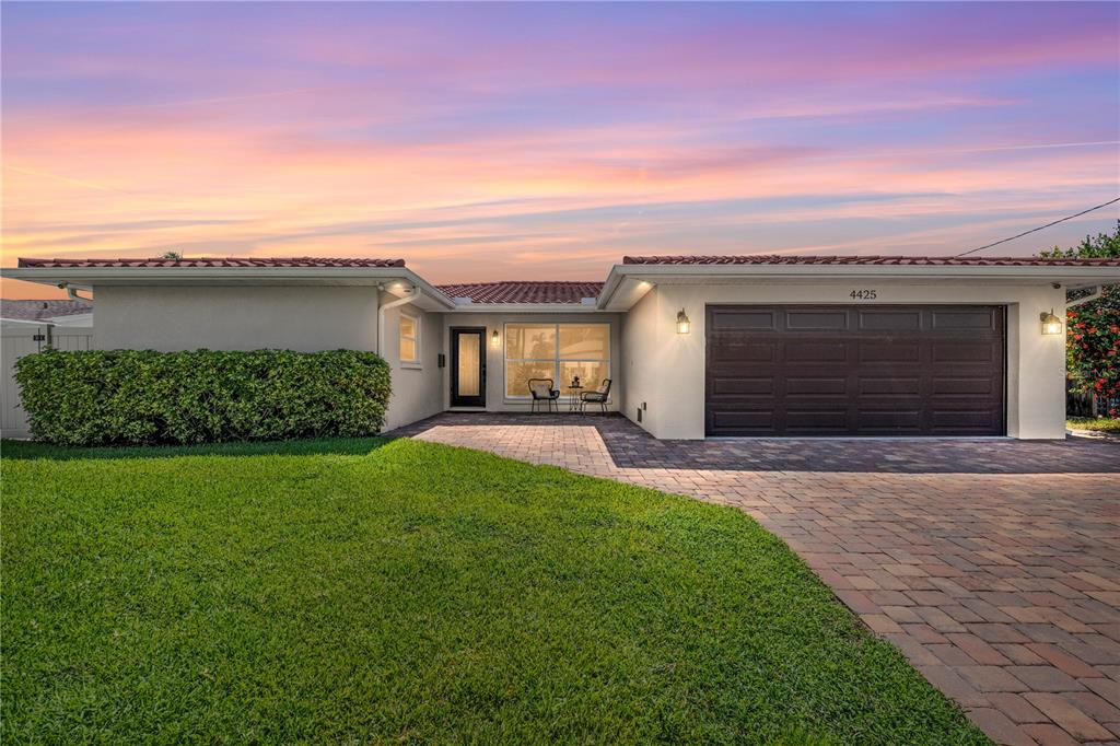 A single-story house with a paved driveway, a dark garage door, and a manicured lawn — 4425 13TH WAY NE, ST PETERSBURG, FL