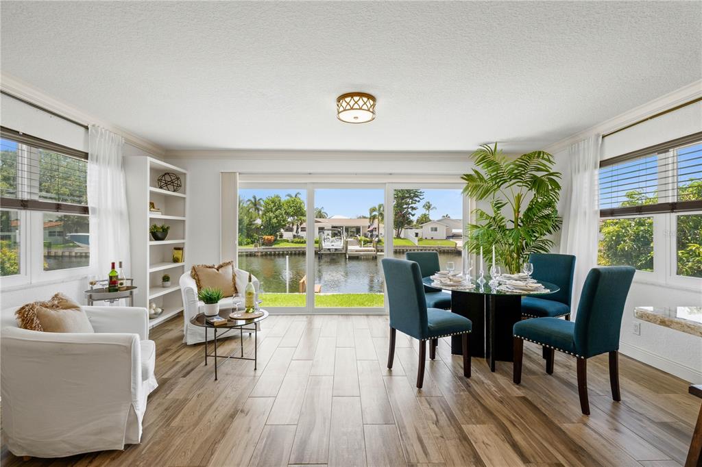 A dining and living area features wood-look tile floors and sliding doors overlooking a canal — 4425 13TH WAY NE, ST PETERSBURG, FL