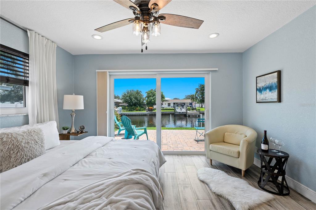 A bedroom with light blue walls, a king bed, and sliding doors overlooking a canal — 4425 13TH WAY NE, ST PETERSBURG, FL