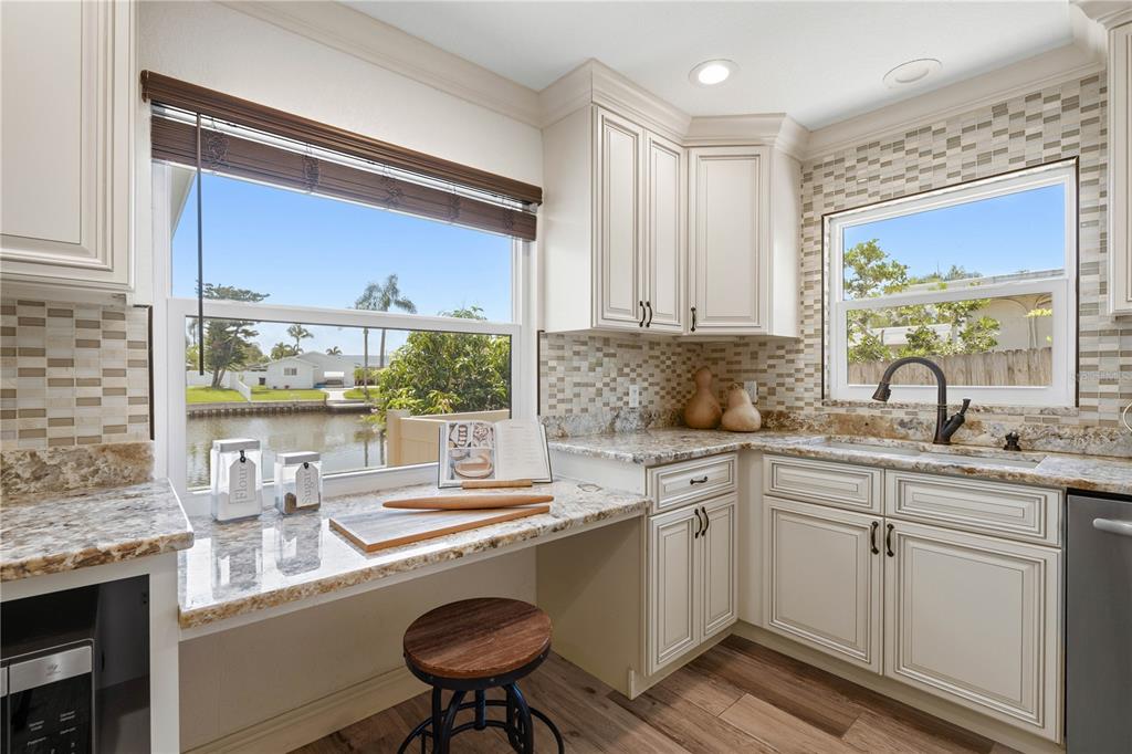 A kitchen features white cabinetry, granite countertops, a tile backsplash, and a view of water — 4425 13TH WAY NE, ST PETERSBURG, FL