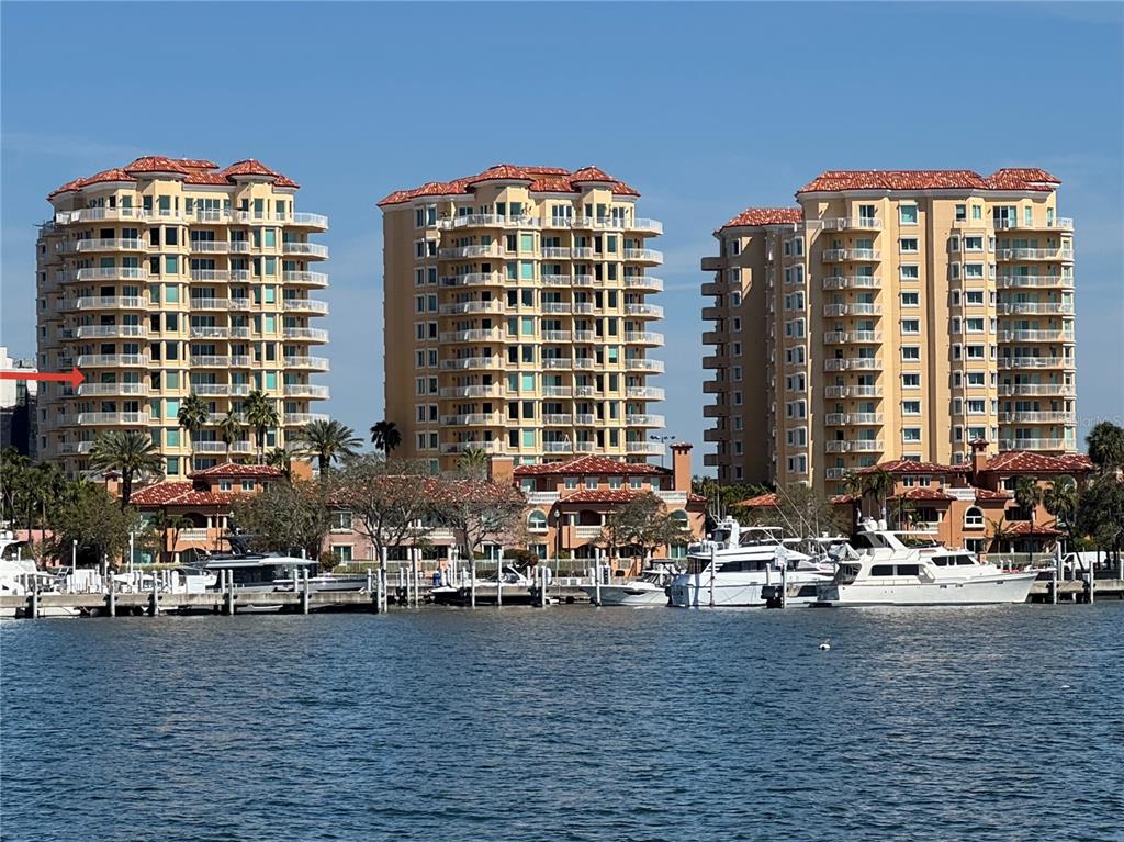 Three tall, tan residential buildings with balconies stand behind a marina on the water — 555 5TH AVENUE NE UNIT 711, ST PETERSBURG, FL