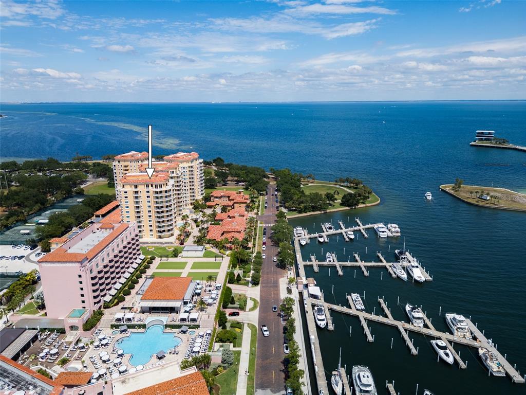 An aerial view shows a tall residential building, a marina, and a swimming pool — 555 5TH AVENUE NE UNIT 711, ST PETERSBURG, FL