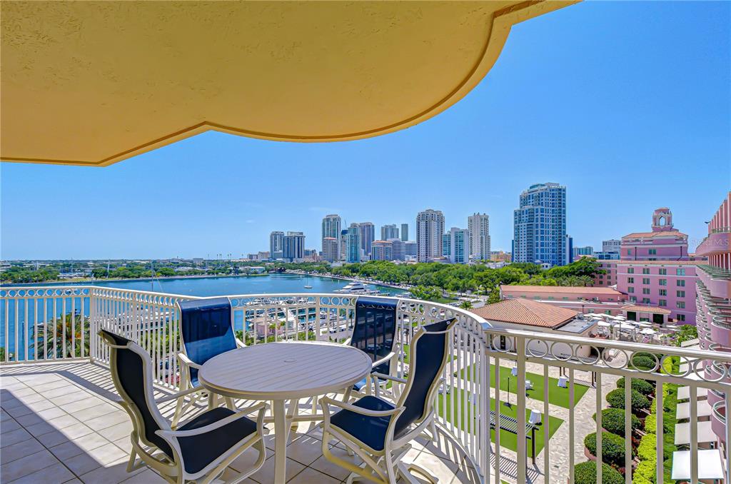 A balcony with a table and chairs overlooks a bay and a city skyline — 555 5TH AVENUE NE UNIT 711, ST PETERSBURG, FL