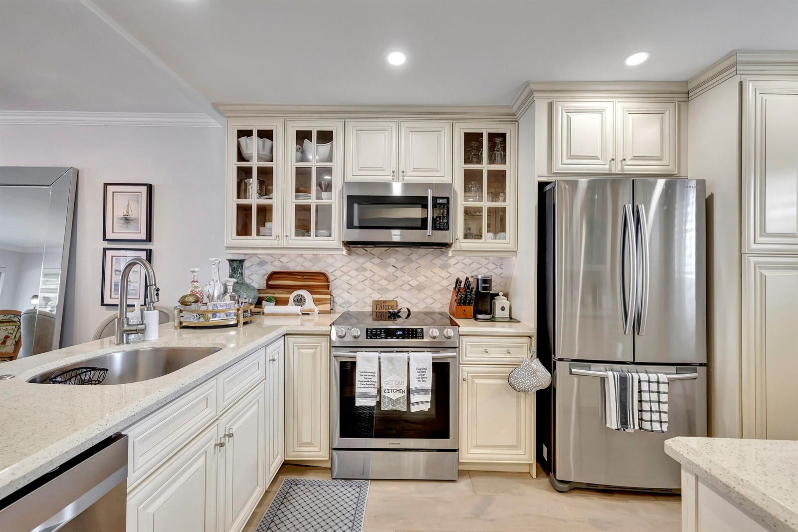 A kitchen features cream-colored cabinets, stainless steel appliances, a quartz countertop, and a tiled backsplash — 1537 E Hillsboro Boulevard # 239, Deerfield Beach FL 33441, DEERFIELD BEACH, FL