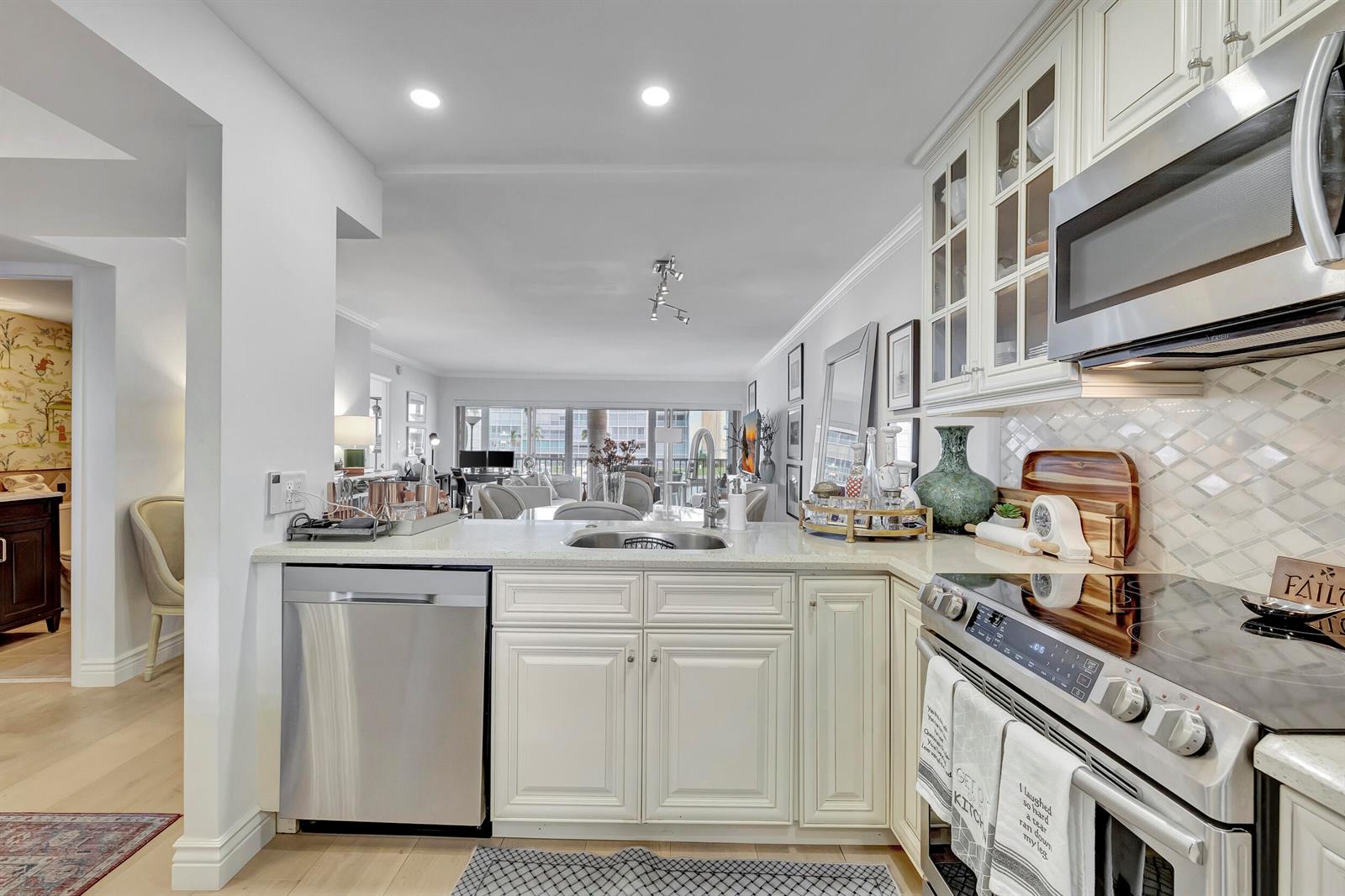 A kitchen with white cabinets, stainless steel appliances, and a view into the living area — 1537 E Hillsboro Boulevard # 239, Deerfield Beach FL 33441, DEERFIELD BEACH, FL