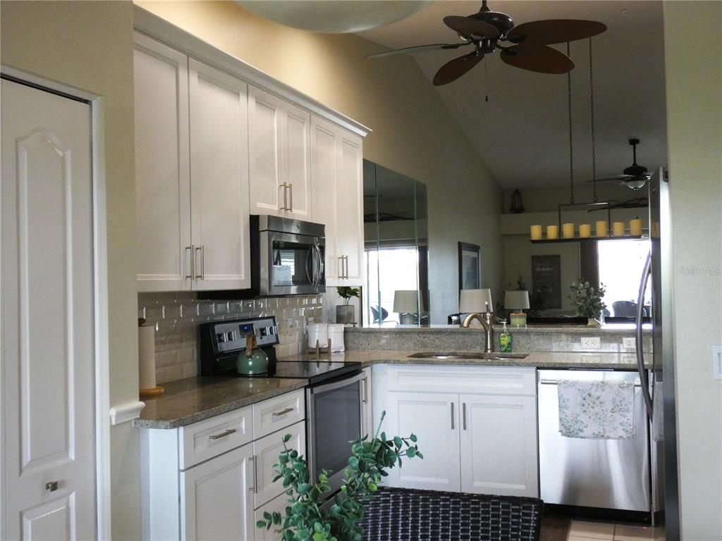 A kitchen features white cabinets, stainless steel appliances, granite countertops, and a vaulted ceiling — 4639 CHAPEL HILL DRIVE UNIT 2924, SARASOTA, FL