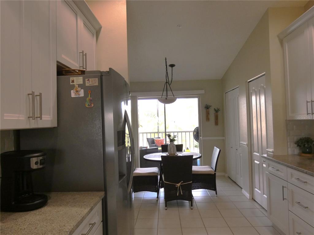 A kitchen with white cabinets and stainless steel appliances opens to a dining area with patio access — 4639 CHAPEL HILL DRIVE UNIT 2924, SARASOTA, FL