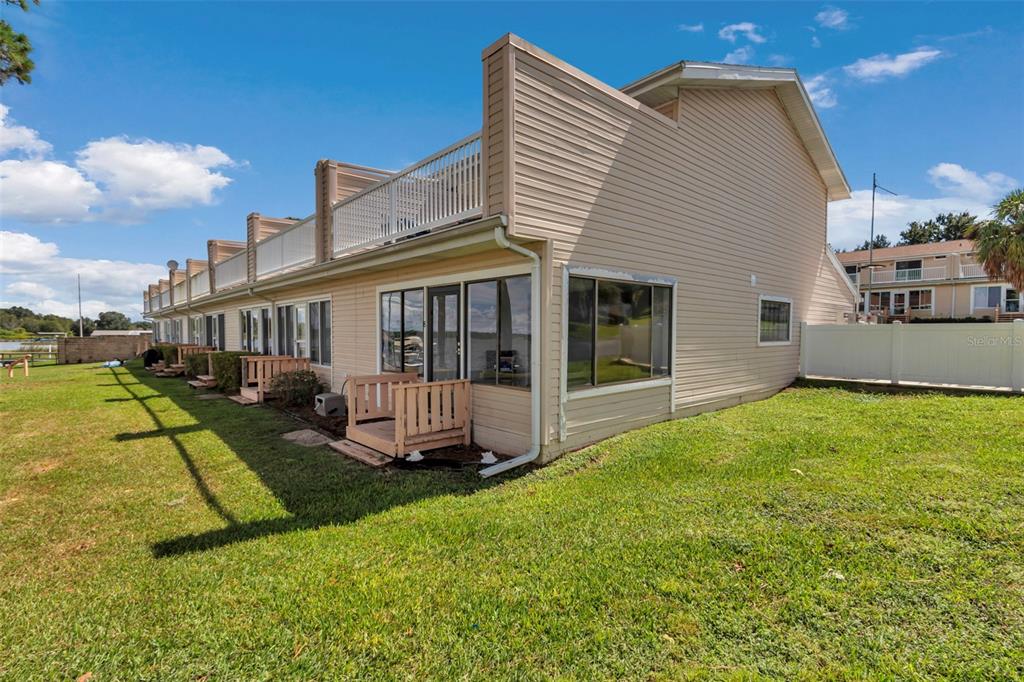 The exterior of a multi-unit townhouse building features beige siding, a second-story balcony, and patios — 11001 SE SUNSET HARBOR RD UNIT A08, SUMMERFIELD, FL