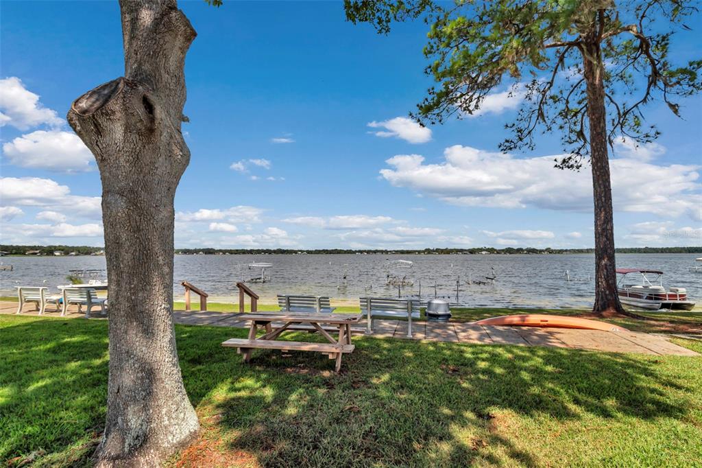A grassy waterfront yard features a picnic table, benches, a kayak, and a boat dock — 11001 SE SUNSET HARBOR RD UNIT A08, SUMMERFIELD, FL