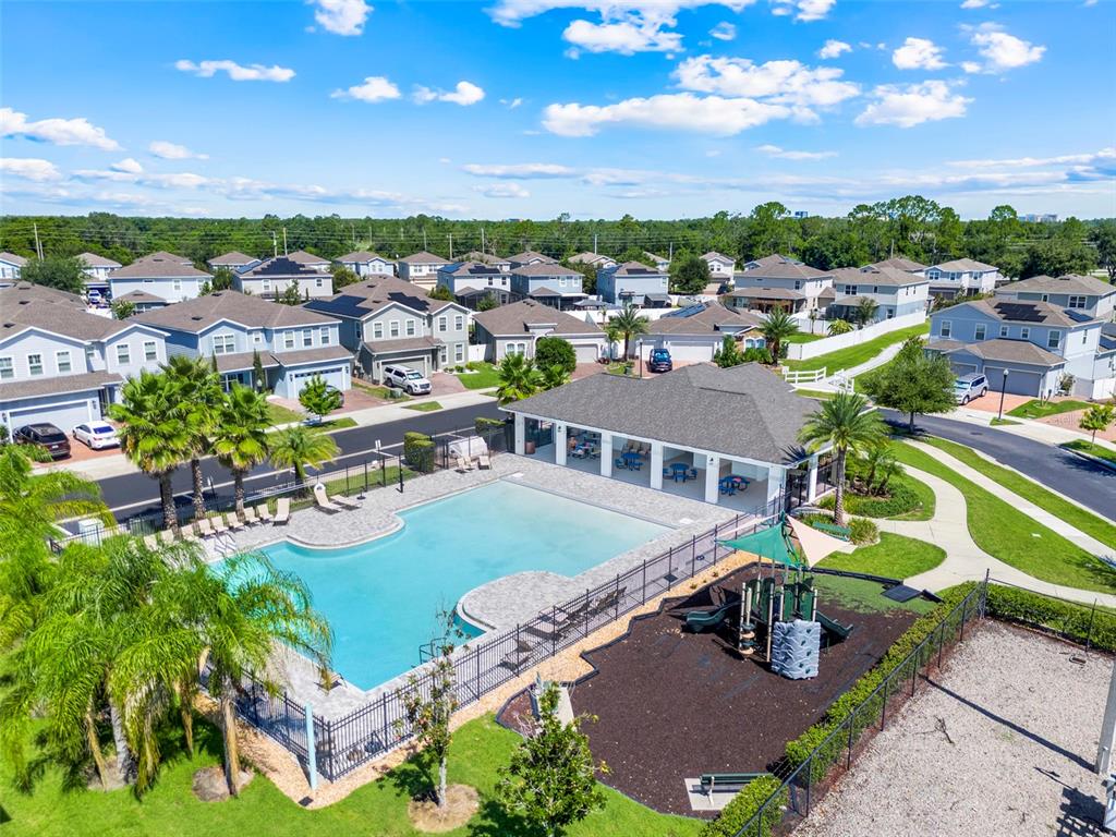 An aerial view of a community swimming pool, playground, and clubhouse surrounded by suburban houses — 4347 SILVER CREEK STREET, KISSIMMEE, FL
